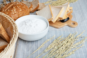 slide white bread ,whole wheat with whole grain bread and white blow of flour on light blue floor with some fresh wheat.