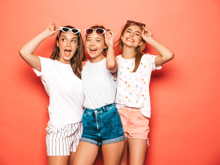 Fototapeta premium Three young beautiful smiling hipster girls in trendy summer clothes. Sexy carefree women posing near pink wall in studio. Positive models going crazy and having fun