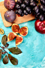 Autumn frame background. Autumn food still life with season fruits grape, red apples and figs on a blue table. Thanksgiving day.