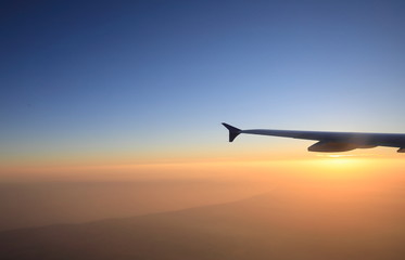 Fototapeta na wymiar Sunset flight view with airplane wing silhouette