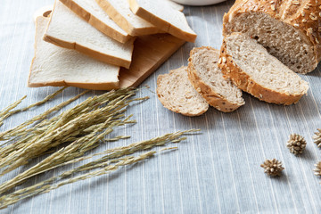 slide white bread ,whole wheat with whole grain bread and white blow of flour on light blue floor with some fresh wheat.