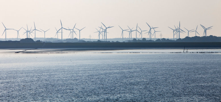 silhouette of wind turbine park on shore of north sea in german part ostfriesland