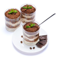 Classic tiramisu dessert in a glass cup on the plate and pieces of chocolate on white background with clipping path