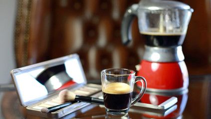 Cup of coffee with the phone and make-up set, shadow palette, and brushes, moka pot coffee