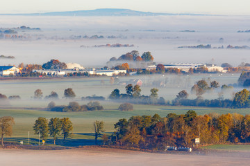 Fog over the countryside with a road and buildings