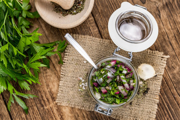 Wooden table with Chimichurri (detailed close-up shot; selective focus)