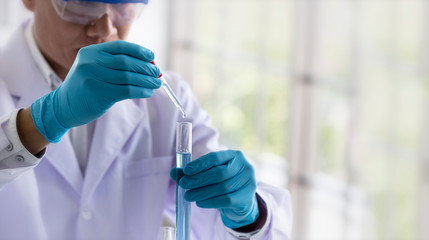 Laboratory research concept; scientist dropping chemical reagent into test tube. Research in chemical laboratory.