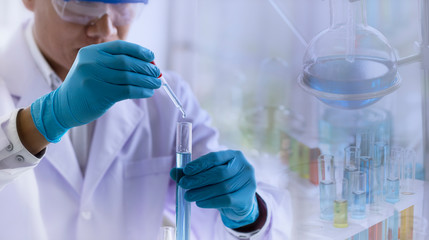 Fototapeta premium Laboratory research concept; scientist dropping chemical reagent into test tube with lab glassware background. Research in chemical laboratory.