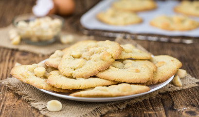 Old wooden table with fresh Macadamia Cookies (close-up shot; selective focus)