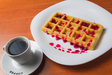 Belgian waffle with raspberry jam on a wooden background. copy space