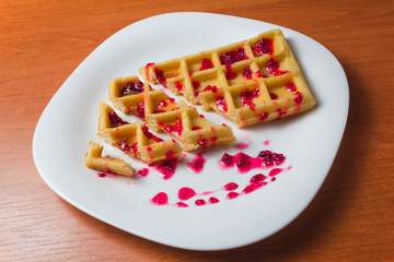 Belgian waffle with raspberry jam on a wooden background. copy space