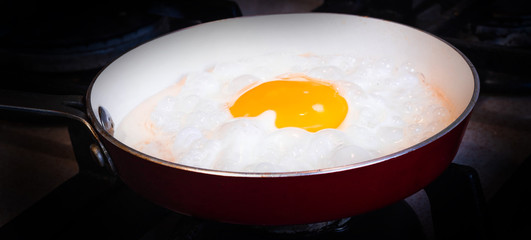 Fried eggs in a small pan on a dark background