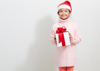 Girl holding a gift box in sweater and santa hat