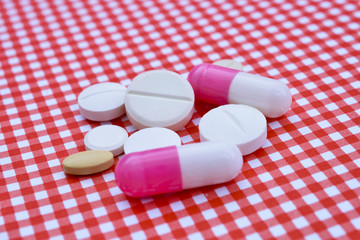 various capsules and pills on a red background