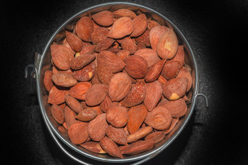 Almonds, Apricot kernels in a bucket on a dark background