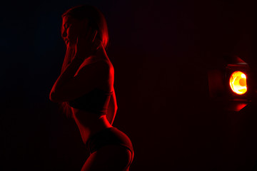 Young beautiful woman in lingerie posing in red back light