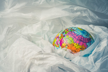 The concept of reducing plastic bags use: Modeled globes are sunk in many white plastic bags. Meaning, plastic bags are about to overflow the world.