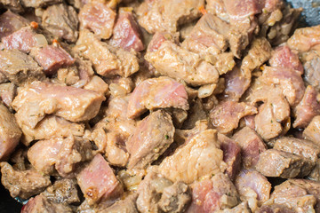 Fresh pieces of red veal tenderloin with onions are roasted in large cauldron for pilaf.