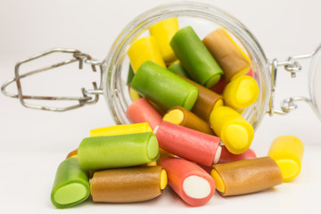 gummy tubes in yellow, pink, green and brown in a glass jar