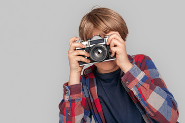 Freestyle. Young boy standing isolated on grey taking photo with camera