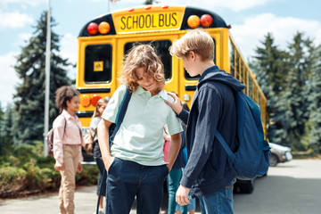 Classmates going to school by bus boy holding friend's shoulder talking supporting close-up