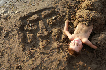 Boy buried in sand on beach