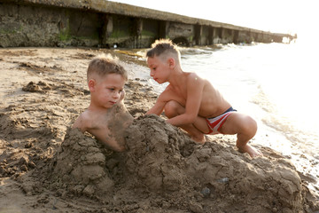 Child burying his brother in sand