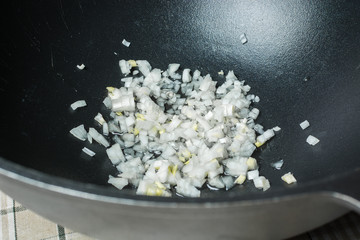 Sliced white onions in oil for frying in cast iron cauldron for pilaf.