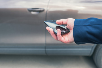 Customer hand holding mobile phone for opening car door. Car sharing service or rental concept.