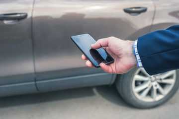 Customer hand holding mobile phone for opening car door. Car sharing service or rental concept.