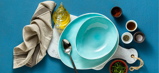 banner of set the table with empty plates and glasses, spices and herbs. on the blue. shot from above. copy space