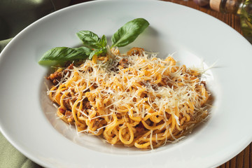 Bolognese pasta with red sauce, parmesan, parmesan and minced meat. Italian spaghetti in a white plate on a wooden background. Close up, slective focus. Food photo background