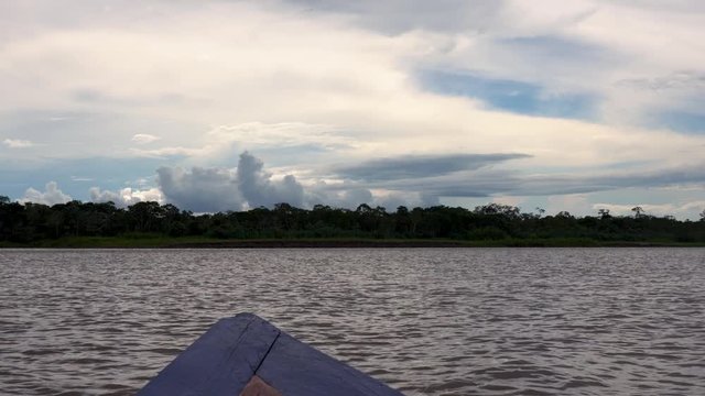 Front View: Boat sails on the Amazon River in Brazil on a cloudy day in the jungle. Beautiful landscape in peruvian rainforest border.