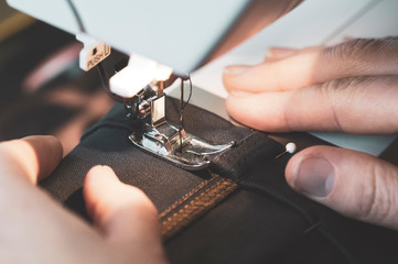 sewing machine close-up and women's hands, light from the lamp, tinted image, selective focus