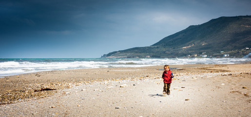 Fototapeta na wymiar Cheerful boy walking on beach