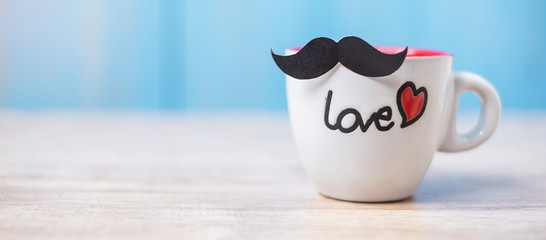 coffee cup with Black mustache on wood table background in the morning. Father, International men day, Prostate Cancer Awareness and World cancer day concept