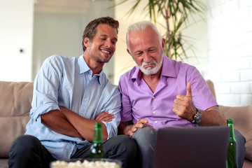 Father and son watch football game on laptop