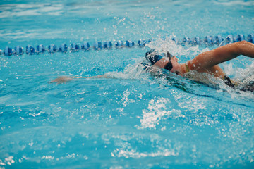 Young woman swimmer swims in swimming pool