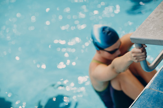 Young woman swimmer getting ready for competition and swim in swimming pool