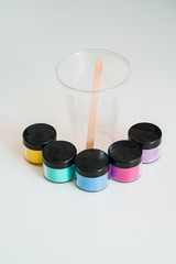 Mixing colors wooden spoon in transparent plastic cup