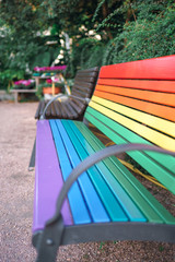 Fototapeta na wymiar LGBT Lesbian Gay Bisexual and Transgender themed park bench rainbow colors