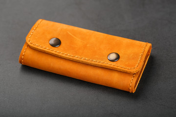 Brown cover wallet for keys made of genuine nubuck leather on a dark background. Handmade leather items. Handmade rivets and seam closeup