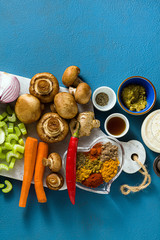 Fototapeta na wymiar Ingredients for cooking Indian curry from vegetables, pumpkins and mushrooms on a blue background and spices. shot from above. copy space
