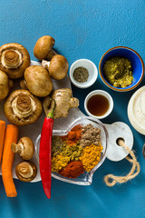Ingredients for cooking Indian curry from vegetables, pumpkins and mushrooms on a blue background and spices. shot from above. copy space