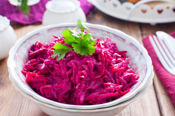 Boiled beet salad with garlic and mayonnaise in a bowl on a wooden table, horizontal