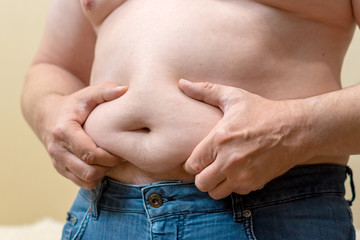 Naklejka premium Belly of a fat man in jeans close-up