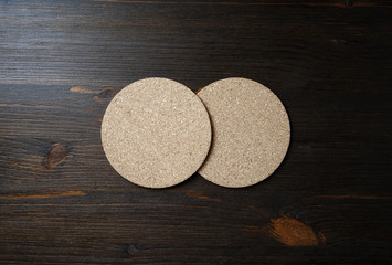 Photo of two blank cork beer coasters on wooden background. Flat lay.