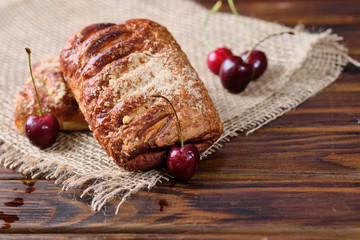 Puffs with cherry jam on burlap on a wooden background. Rustic style