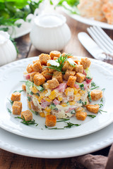 Salad with smoked sausage and crackers on a white plate in a portion serving, selective focus