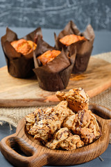 caramel waffles on a wooden plate and cupcakes on a gray background. Rustic style